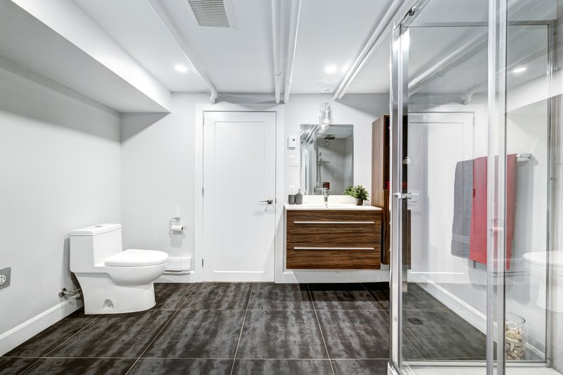 Baño con regadera amplio con pisos de madera oscura