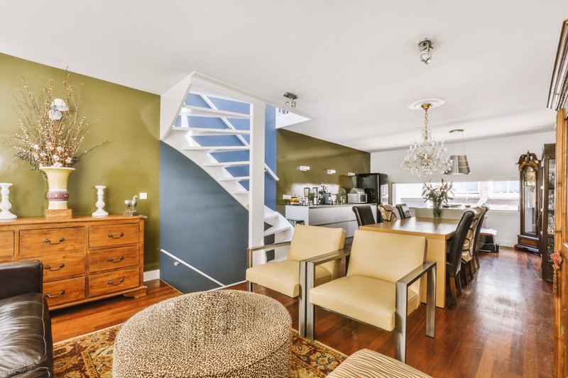 Primer piso de una casa acogedora con sillas, escaleras de fondo y paredes con colores vibrantes