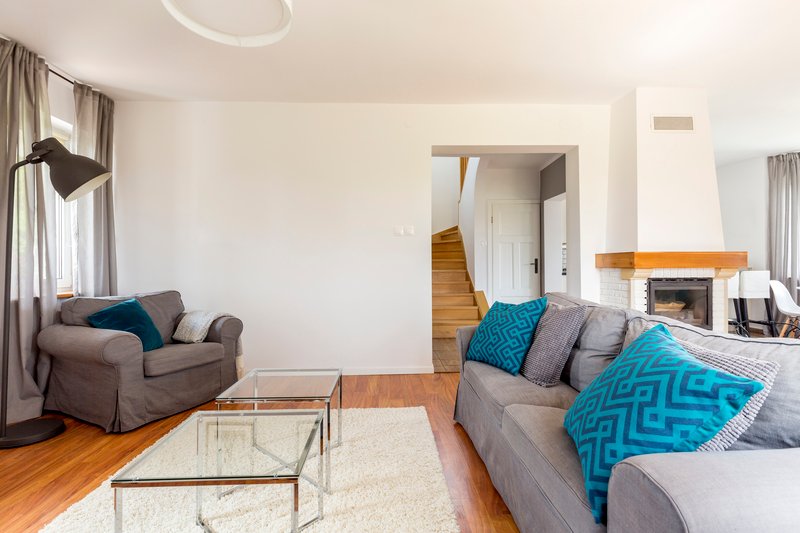 Sala acogedora con sofa gris y almohadas azules condesas de cristal